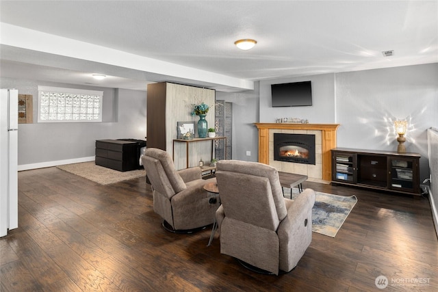 living area with baseboards, visible vents, wood finished floors, and a tile fireplace