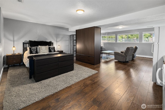 bedroom with baseboards, a textured ceiling, and dark wood-type flooring
