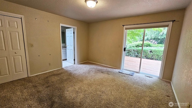 spare room with a textured ceiling, visible vents, carpet floors, baseboards, and a textured wall