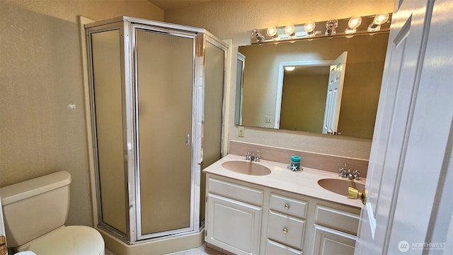 full bathroom featuring a sink, a shower stall, toilet, and double vanity
