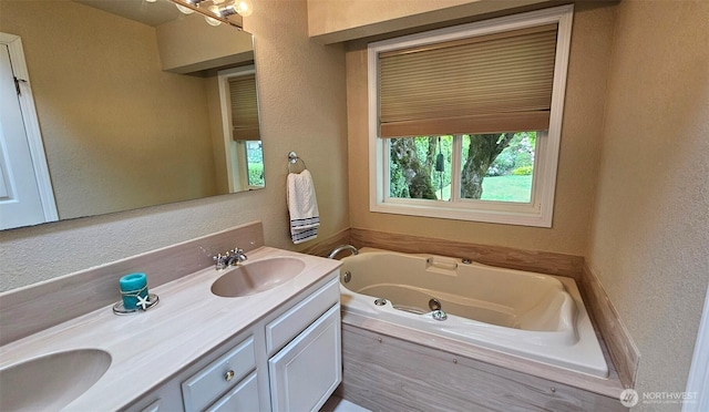 full bathroom with double vanity, a whirlpool tub, a textured wall, and a sink