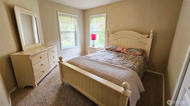bedroom with baseboards, carpet flooring, and a textured wall
