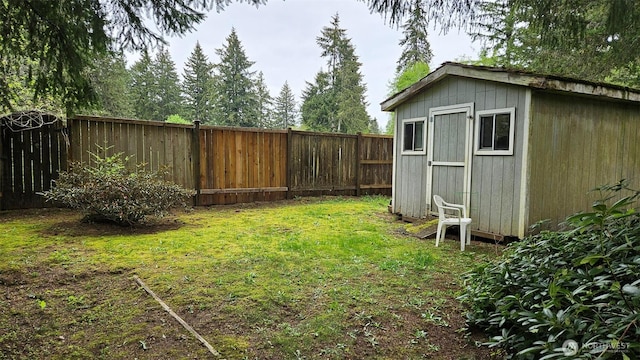 view of yard with a storage unit, a fenced backyard, and an outbuilding