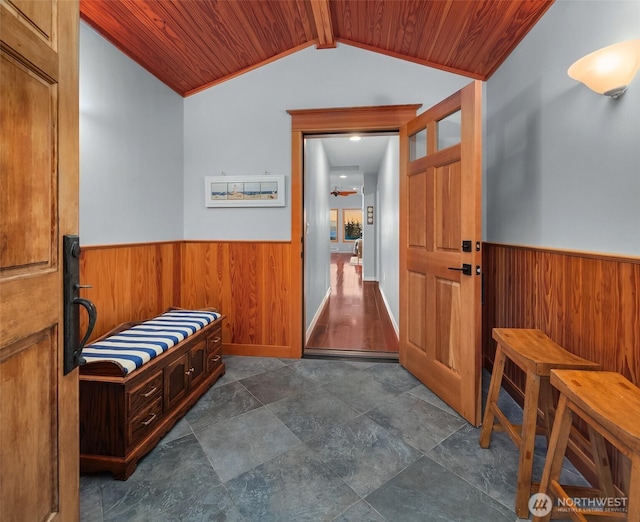 interior space featuring lofted ceiling with beams, wainscoting, wood walls, and wood ceiling