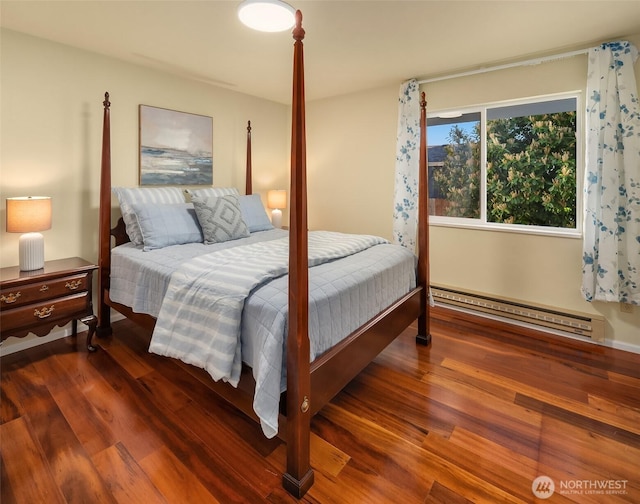 bedroom with a baseboard heating unit and wood finished floors