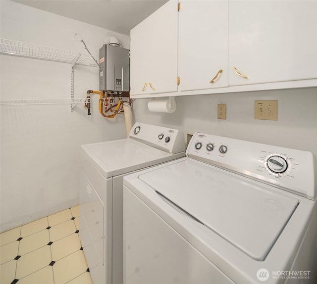 laundry room featuring water heater, washing machine and clothes dryer, and cabinet space