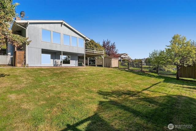 back of property with a storage unit, fence, an outdoor structure, and a yard