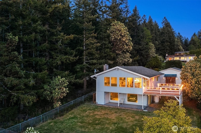 back of house with a yard, a fenced backyard, a chimney, a deck, and a wooded view