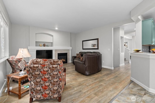 living area with light wood-style floors, recessed lighting, baseboards, and a tile fireplace