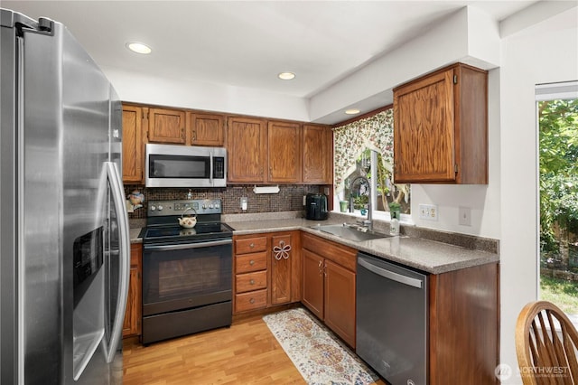 13103 SE 261st Pl, Kent, WA 98030 - kitchen featuring brown cabinetry, decorative backsplash, light wood-style floors, a sink, and stainless steel appliances