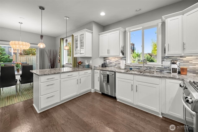 kitchen featuring dark wood finished floors, a sink, white cabinets, a peninsula, and stainless steel appliances