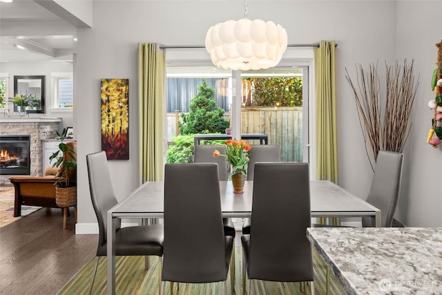 dining area featuring a healthy amount of sunlight, baseboards, a fireplace, and dark wood-style floors