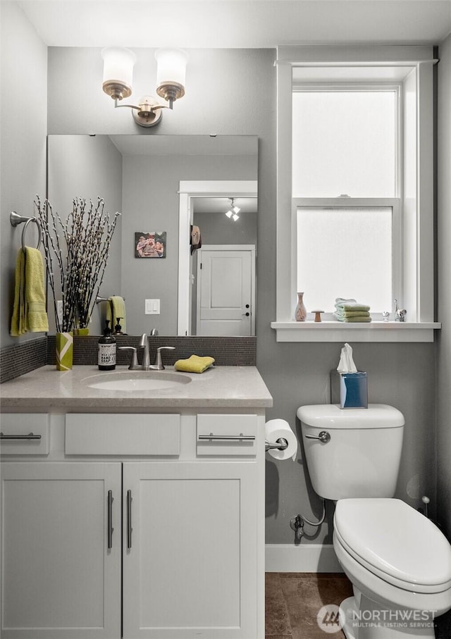 bathroom with toilet, baseboards, and vanity