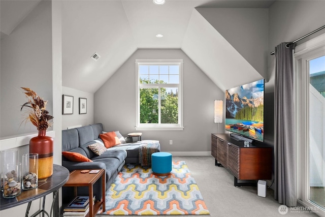 living area with plenty of natural light, light carpet, vaulted ceiling, and visible vents