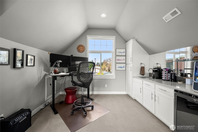 office space with visible vents, vaulted ceiling, a sink, baseboards, and light carpet