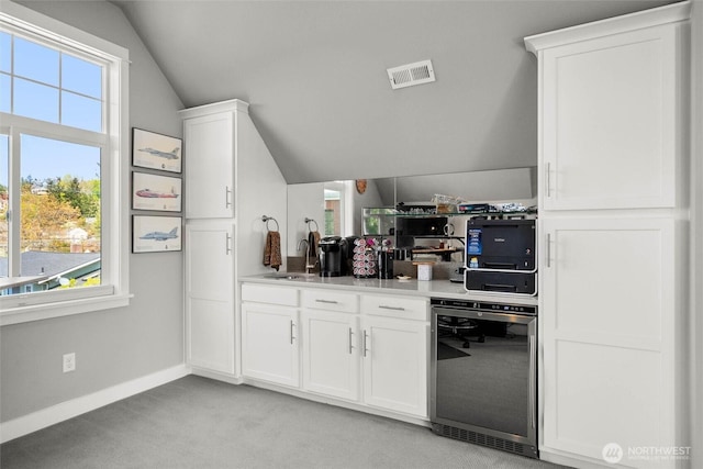 bar with wine cooler, light carpet, vaulted ceiling, and a healthy amount of sunlight
