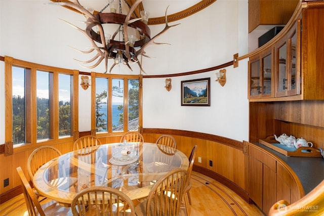 4385 Wildwood Ln, Anacortes, WA 98221 - dining space featuring a chandelier, a wainscoted wall, wood walls, and light wood finished floors