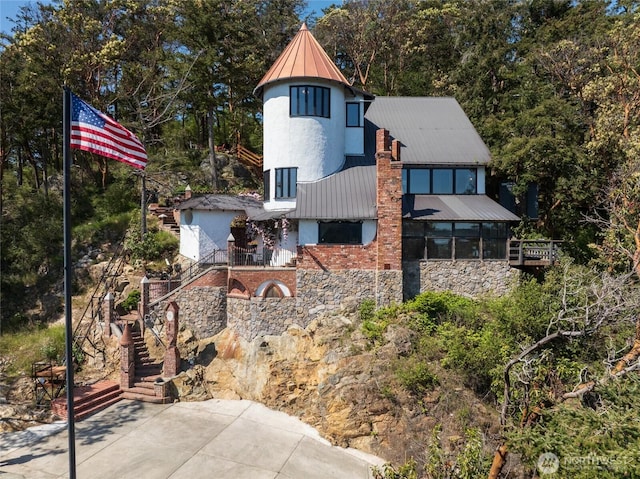 4385 Wildwood Ln, Anacortes, WA 98221 - view of front of home featuring stairway, metal roof, a standing seam roof, stone siding, and stucco siding