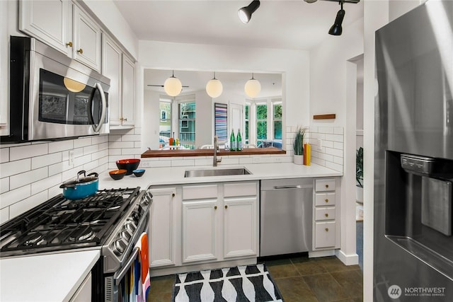 kitchen with tasteful backsplash, decorative light fixtures, appliances with stainless steel finishes, light countertops, and a sink
