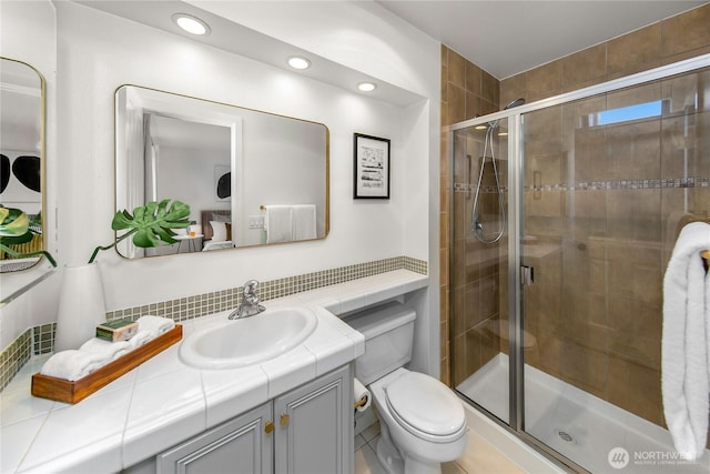 bathroom featuring toilet, vanity, a shower stall, and recessed lighting