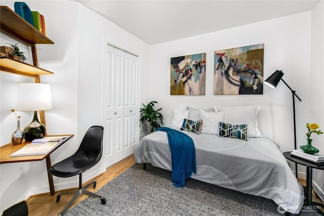 bedroom with light wood-style floors, baseboards, and a closet