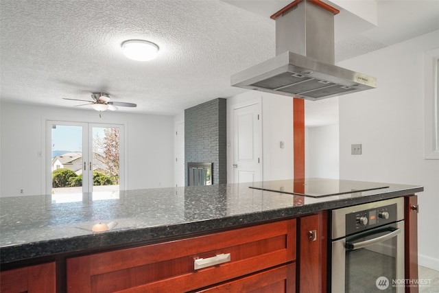 8305 NW Fruit Valley Rd, Vancouver, WA 98665 - kitchen with reddish brown cabinets, island range hood, a ceiling fan, a textured ceiling, and stainless steel oven