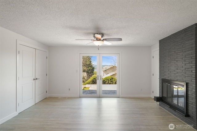 8305 NW Fruit Valley Rd, Vancouver, WA 98665 - unfurnished living room with a brick fireplace, a ceiling fan, light wood-style flooring, and baseboards