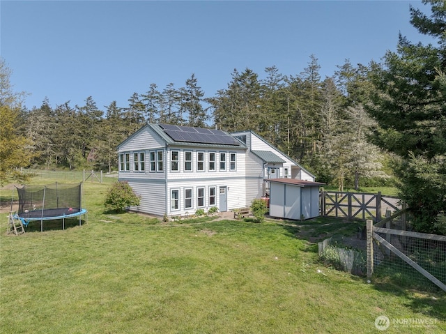486 Wren Rd, Lopez Island, WA 98261 - rear view of property with a trampoline, an outbuilding, a yard, a storage shed, and roof mounted solar panels