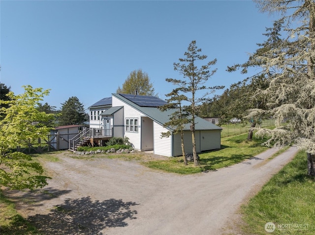 486 Wren Rd, Lopez Island, WA 98261 - view of property exterior featuring an outbuilding, a storage unit, driveway, stairs, and solar panels