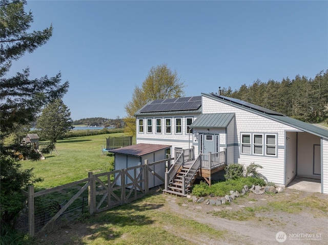 486 Wren Rd, Lopez Island, WA 98261 - view of front of house featuring a gate, fence, metal roof, roof mounted solar panels, and a front lawn