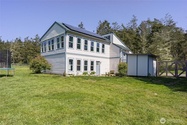 486 Wren Rd, Lopez Island, WA 98261 - rear view of property with an outdoor structure, a trampoline, solar panels, fence, and a yard