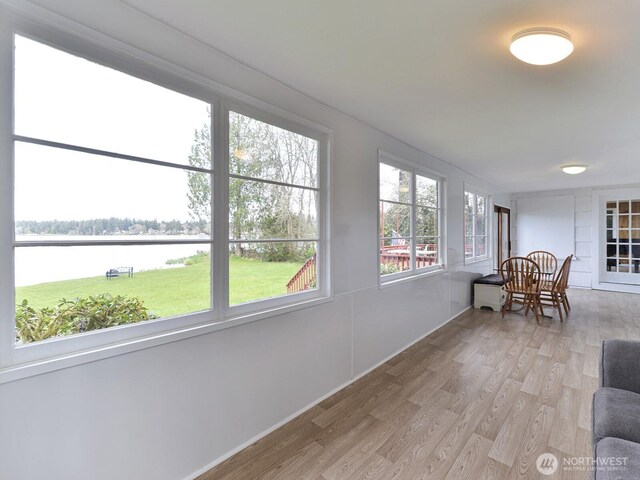 sunroom with a water view and wood finished floors