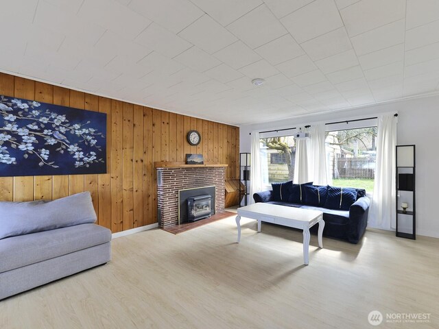 living area featuring wooden walls, baseboards, a wood stove, and wood finished floors