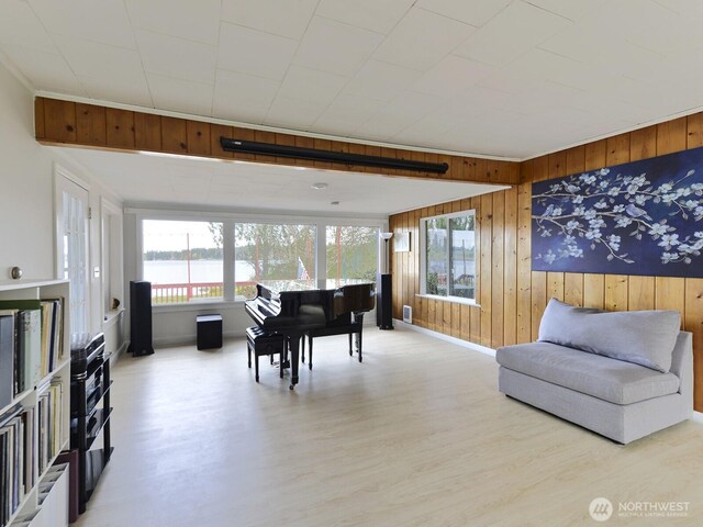 interior space featuring a water view, baseboards, wood walls, and wood finished floors