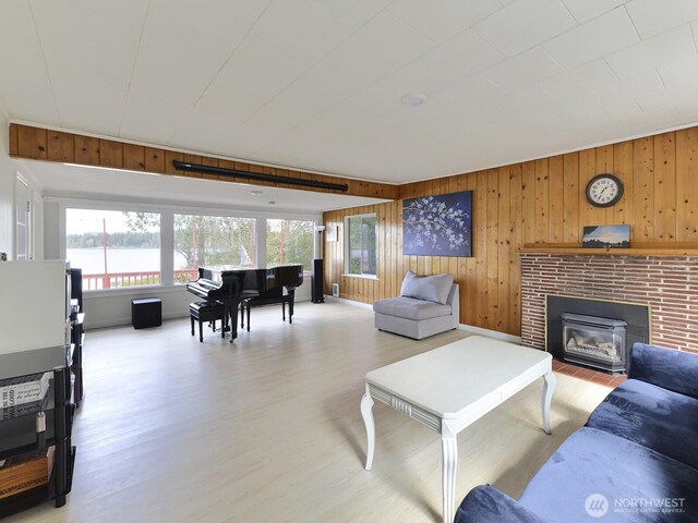 living room with wooden walls, a water view, a brick fireplace, and light wood-style flooring