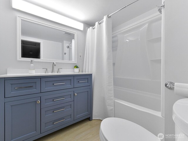 bathroom featuring vanity, toilet, shower / bathtub combination with curtain, wood finished floors, and visible vents