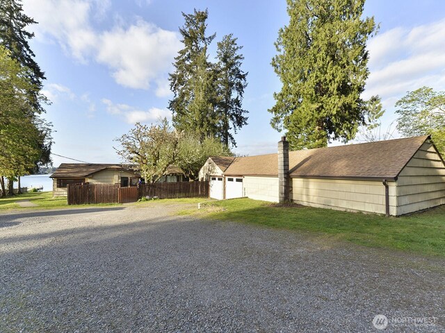 view of front of house featuring fence, driveway, a chimney, and a garage