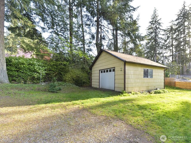 detached garage featuring fence and driveway