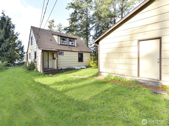 rear view of property with a lawn and roof with shingles
