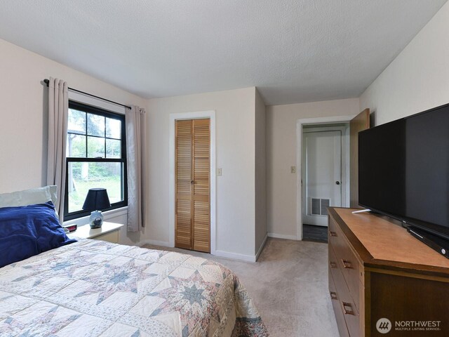 bedroom with visible vents, a closet, baseboards, light colored carpet, and a textured ceiling