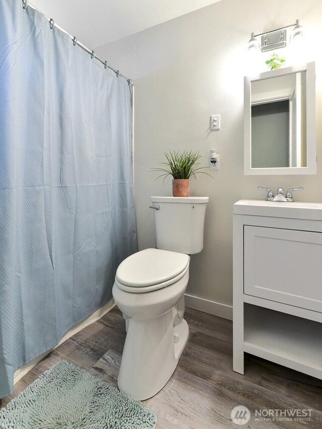 bathroom with vanity, wood finished floors, toilet, baseboards, and a shower with curtain