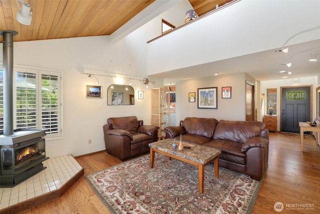 living room featuring a wood stove, wood ceiling, wood finished floors, and vaulted ceiling