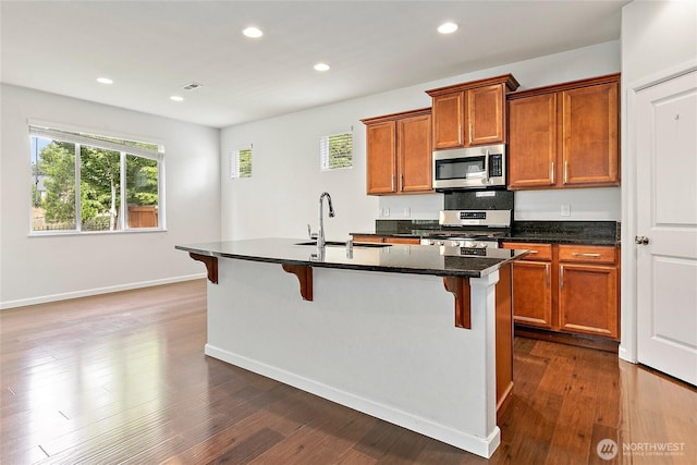 4000 Cameron Dr NE, Lacey, WA 98516 - kitchen with stainless steel appliances, a kitchen bar, brown cabinetry, recessed lighting, and dark wood finished floors