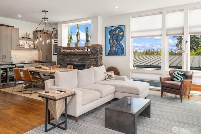 living room with recessed lighting, a fireplace, light wood-style flooring, and wine cooler