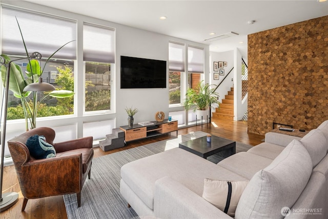 living area with stairs, wood finished floors, and plenty of natural light