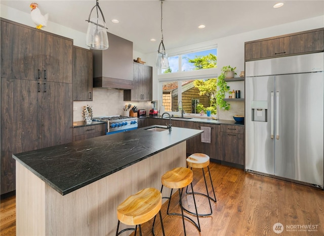 kitchen with open shelves, a center island with sink, appliances with stainless steel finishes, and a sink
