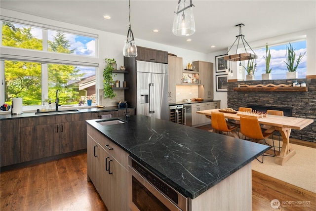 kitchen featuring a sink, open shelves, an island with sink, and built in appliances