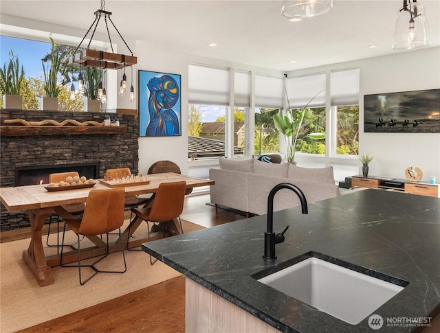 kitchen with decorative light fixtures, a wealth of natural light, wood finished floors, and a sink