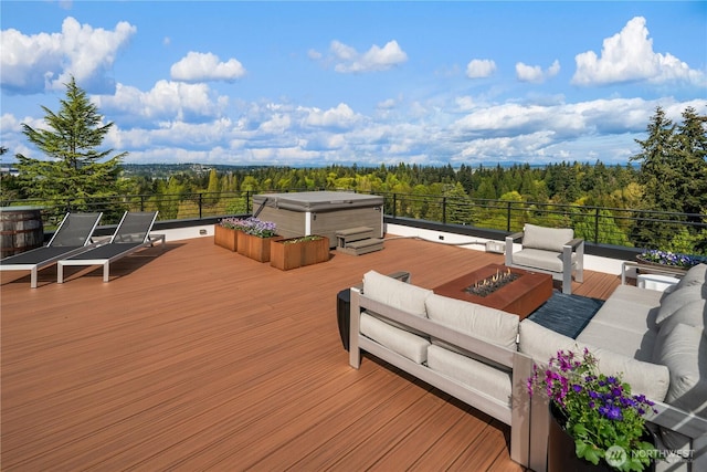 wooden deck with a covered hot tub, a wooded view, and an outdoor living space