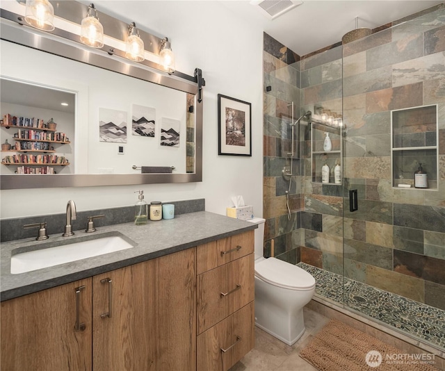 bathroom featuring toilet, a stall shower, visible vents, and vanity
